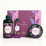 The Body Shop Dewberry Essentials bath and body gift set featuring a dark green bath and shower gel bottle, a purple hand wash tube, a round tin of bath salts, and a matching purple gift box with floral illustrations.
