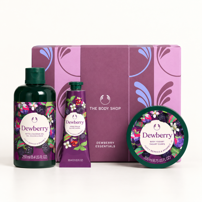 The Body Shop Dewberry Essentials bath and body gift set featuring a dark green bath and shower gel bottle, a purple hand wash tube, a round tin of bath salts, and a matching purple gift box with floral illustrations.
