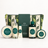 The Body Shop White Tea & Elderflower gift set featuring a green and cream patterned zip pouch, a dark green card, a hand cream tube, a shower gel bottle, a bath bomb tin, and two body butter tins on a white background.