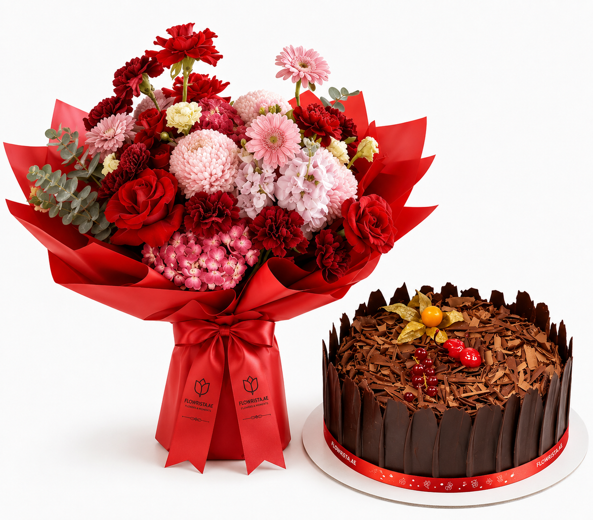 A red and pink flower bouquet wrapped in red paper with a red ribbon, placed beside a chocolate cake with chocolate shavings and a red ribbon on a white background.