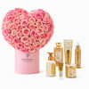 A heart-shaped bouquet of pink roses in a pink cylindrical box branded FLOWWRISTA, displayed with several matching bath and body products in gold and floral packaging on a clean white background.