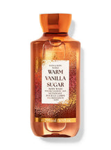 A bottle of Bath & Body Works Warm Vanilla Sugar body wash, featuring a translucent amber-orange bottle with a gold glitter pattern and a white label in the center, set against a plain white background.