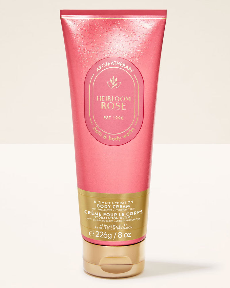 A pink squeeze tube of Heirloom Rose Aromatherapy body cream with a gold cap, set against a clean off-white background.