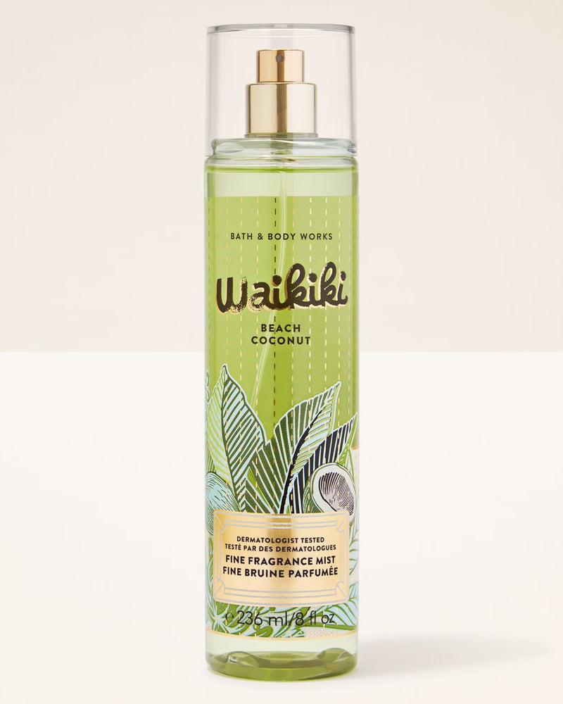 A bottle of Bath & Body Works Waikiki Beach Coconut Fine Fragrance Mist, featuring a light green tropical leaf and coconut illustration on the label, with a gold spray nozzle and clear cap, set against a plain off-white background.
