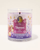 Disney Princess Rapunzel Bath & Body Works soy wax candle in a clear glass jar with a purple and pink label, lit candle shown against a light beige background.