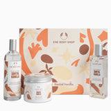 The Body Shop Santal Vanilla gift set featuring a fragrance oil bottle, a body cream jar, and a body wash bottle arranged in front of a decorative Santal Vanilla gift box on a white background.