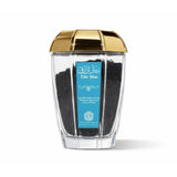 Clear container with gold lid filled with black powder, featuring a blue label on a white background.