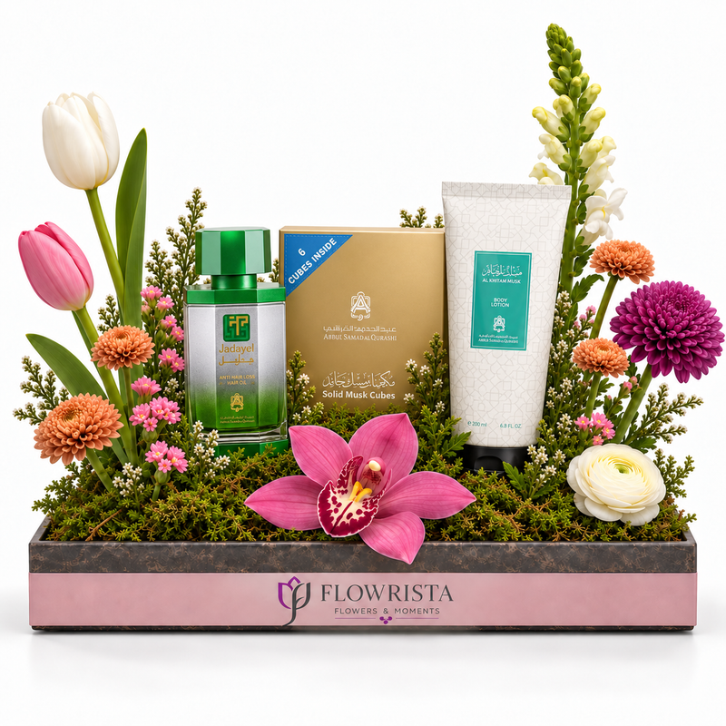 A floral gift basket arrangement by Flowrista featuring a green and white facial mask care set, a gold box, and a white tube, styled with tulips, chrysanthemums, and an orchid in a pink and gray tray on a white background.