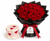 A large bouquet of red roses wrapped in black paper with a red ribbon and a tag reading FLOWWRISTA, shown next to a small pink and white heart-patterned cake on a white background.
