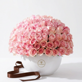 100 fresh pale pink roses arranged in a full dome in a white Flowrista ceramic vase