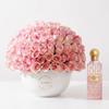 Pink Diamond Sakura 150 ml perfume beside 100 fresh pink roses in a white Flowrista ceramic vase