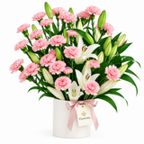 Flowrista pink carnations and white lilies with green foliage in a white container and pink bow