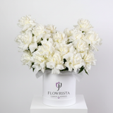 Flowrista white peonies overflowing white cylindrical box with white satin ribbon bow