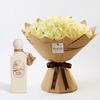 Riviera Sunset perfume beside 100 white roses in brown wrapping with a Flowrista gift tag