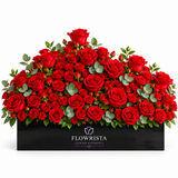 Fresh red roses with eucalyptus greenery arranged in a black rectangular Flowrista planter