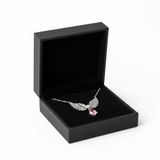 Angel wings necklace with pink stone in black jewelry box on white background