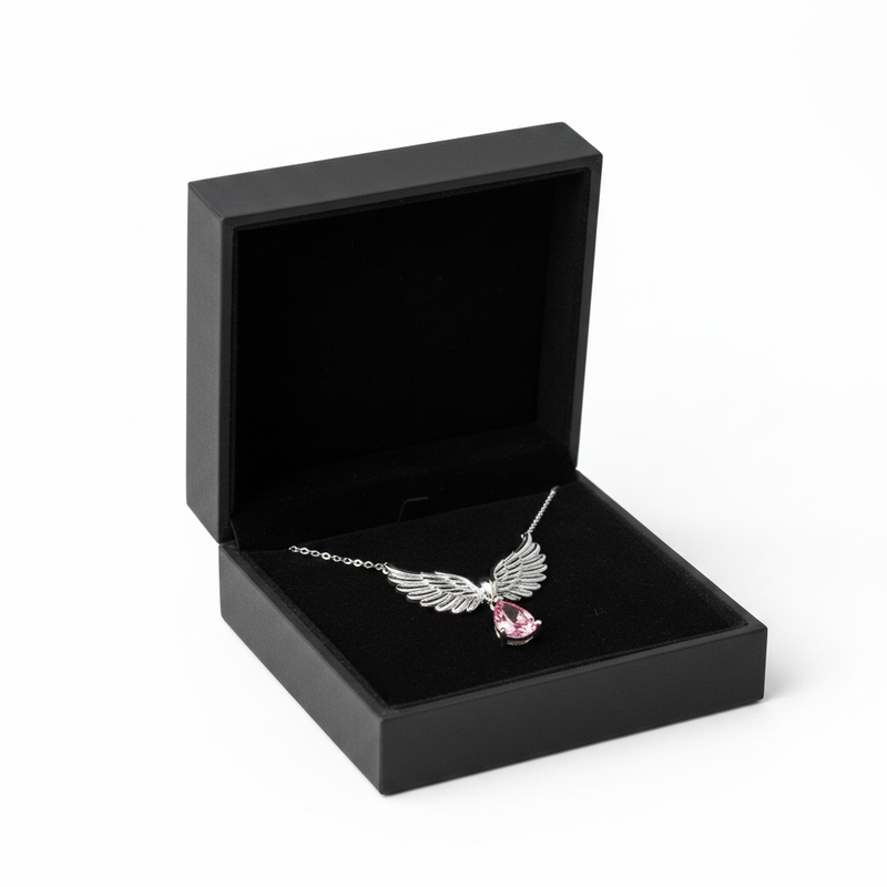 Angel wings necklace with pink stone in black jewelry box on white background