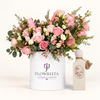 Riviera Sunset perfume beside a white Flowrista box of pink roses and white blooms