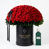 Emerald Soul Diamond perfume beside red roses in a tall black Flowrista box with black ribbon