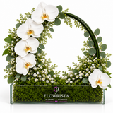 White phalaenopsis orchid wreath arrangement with baby's breath and eucalyptus in a Flowrista glass planter