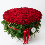 Basket of 1000 red roses with greenery in white wicker, red ribbon and a Flowrista gift tag