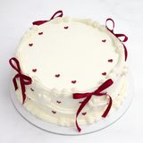 One-kilo Sugar Sweet white birthday cake with burgundy ribbon bows and heart decorations