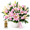 Amir Al Oud Gold perfume beside Flowrista pink roses and pink-and-white lilies in a white pot