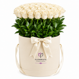 Cream-white roses and greenery in an ivory Flowrista round box with satin bow