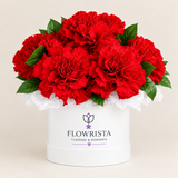 Bright red carnations and greenery in a white Flowrista flower box