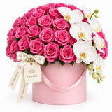 Flowrista pink roses and cascading white orchids in a pink handled flower box with an ivory ribbon